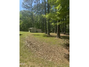 View of an outbuilding on a large lot shaded by large trees at 4501 Duraleigh Rd, Raleigh, NC 27612