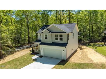 New two-story home featuring a two-car garage and modern gray-green and white color scheme, surrounded by lush trees at 5022 Mockingbird Ln, Sanford, NC 27332