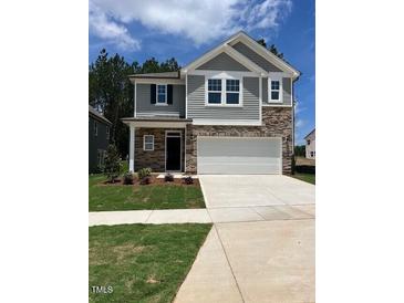 Two-story home featuring a two-car garage, stone accents, gray siding, and a well-manicured front yard at 1003 Shovelhead Dr # 2, Durham, NC 27703