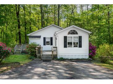 Charming cottage-style home with white siding, black shutters, and mature landscaping at 107 Piquot Dr, Louisburg, NC 27549