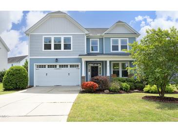 Charming two-story home featuring a well-manicured lawn and a two-car garage, all under a sunny blue sky at 1209 Redwood Valley Ln, Knightdale, NC 27545