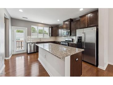 A kitchen featuring stainless steel appliances, granite countertops, and dark wood cabinets at 2027 Hayes Ln, Holly Springs, NC 27540