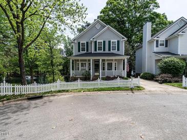 Charming two-story home featuring a white picket fence, covered porch, and landscaped yard with mature trees at 207 Reedhaven Dr, Cary, NC 27513