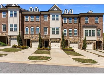 Townhome exterior with brick and stone accents, manicured lawns, driveways, and attached one car garages at 212 Allister Dr, Raleigh, NC 27609