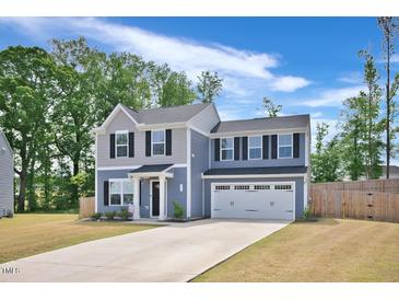 Charming two-story home featuring a two-car garage, manicured lawn, and classic architectural details at 390 Hunting Wood Dr, Angier, NC 27501