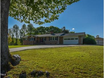 Charming brick home featuring an attached garage and expansive front yard with mature trees at 4170 Buckhorn Rd, Sanford, NC 27330