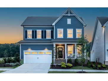 Charming two-story home features a blue exterior, a two-car garage, and a welcoming front porch at 756 Bachelor Gulch Way, Apex, NC 27523