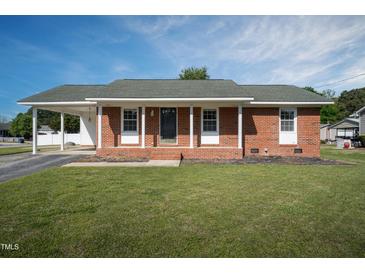 Charming brick home featuring a covered porch with a well-manicured lawn at 101 Pine St, Dunn, NC 28334
