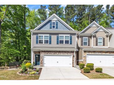 Charming two-story townhome featuring a two-car garage, stone accents, and manicured landscaping at 1230 Wingstem Pl, Raleigh, NC 27607
