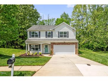 Charming two-story home features a well-manicured lawn, attached two-car garage, and inviting front porch at 1305 Montreux Ct, Mebane, NC 27302