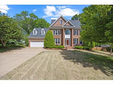Traditional brick home features a well manicured lawn, dormer windows and attached two car garage at 210 Highlands Lake Dr, Cary, NC 27518