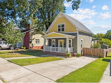Charming home featuring a yellow and gray exterior, a welcoming front porch, and a well-maintained front yard at 215 Haywood St, Raleigh, NC 27601