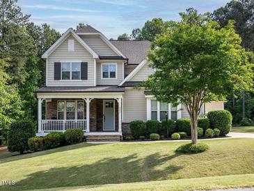 Charming two-story home with a stone-accented porch and well-manicured lawn and mature landscaping at 2317 Emerald Woods Dr, Wake Forest, NC 27587