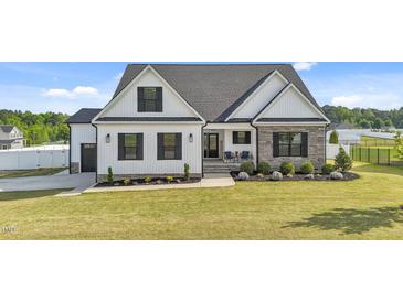 Charming two-story home with well-manicured lawn, stone accents, black shutters, and covered front porch at 30 Devilwood Dr, Four Oaks, NC 27524