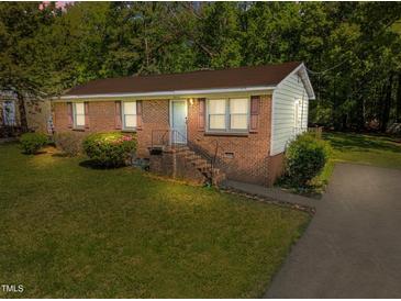Charming brick home features a well-maintained front yard, mature trees, and inviting entrance stairs at 3016 Fields Dr, Raleigh, NC 27603