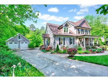 Charming two-story home with a well-manicured lawn, colorful flower beds, and a detached garage at 3581 Boulder Ct, Wake Forest, NC 27587