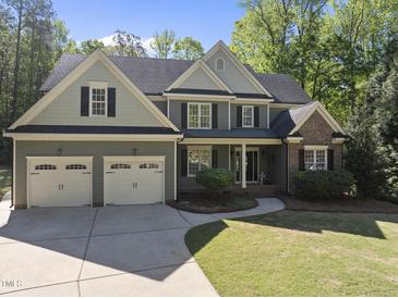 Traditional-style home featuring a three-car garage, manicured lawn, and a welcoming front porch at 359 Heather Bluffs Dr, Garner, NC 27529