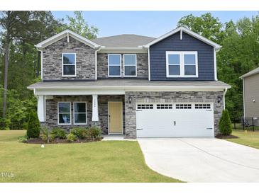 Beautiful two story home featuring a stone and blue shingle facade, a well manicured lawn and a two-car garage at 3804 Delves Ln, Raleigh, NC 27616