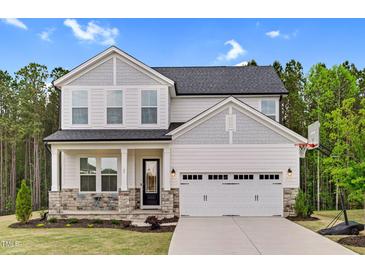 Charming two-story home featuring stone accents, a two-car garage, and a welcoming front porch at 67 Comfort Ct, Fuquay Varina, NC 27526