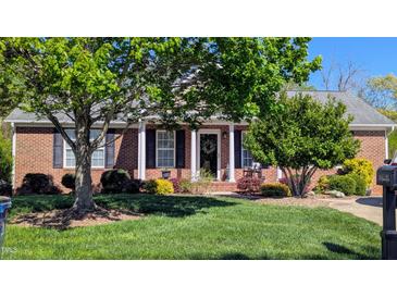 Charming brick home with a lush green lawn, mature trees, and a welcoming front porch at 738 Aspenwood Dr, Graham, NC 27253