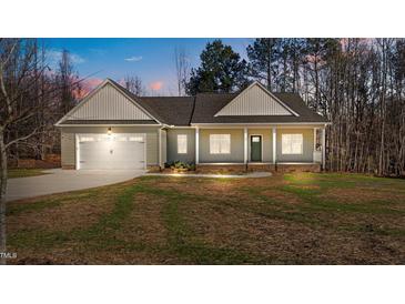Charming single-story home featuring a two-car garage and a welcoming front porch at dusk at 95 Leisure Ln # 9, Louisburg, NC 27549