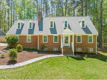Charming brick home featuring dormer windows, a landscaped yard, and a welcoming front entrance at 10609 Lowery Dr, Raleigh, NC 27615