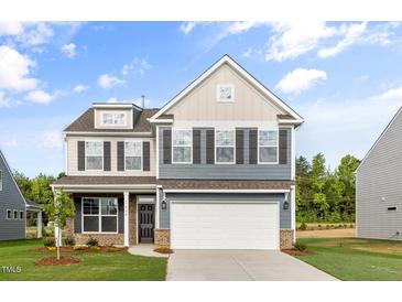 Charming two-story home features a two-car garage and a mix of neutral siding with dark shutters at 1302 Cricket St, Elon, NC 27244