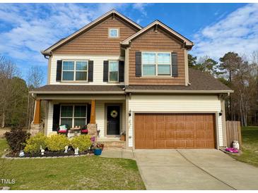 Charming two-story home with a well-manicured lawn, covered porch, and attached two-car garage at 1320 Double Oak Ln, Willow Springs, NC 27592