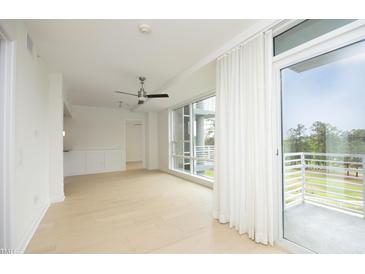 Bright, open living room featuring hardwood floors, ceiling fan, and a sliding glass door to a private balcony at 2402 Environ Way # Bldg 2000, Chapel Hill, NC 27517
