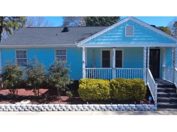 Charming blue home featuring a cozy front porch, well-maintained landscaping, and stone garden border at 307 S Smithfield Rd, Knightdale, NC 27545