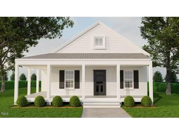 Charming home with a covered porch, black shutters and door, surrounded by lush greenery and mature trees at 329 Green Pines Estates Dr, Kenly, NC 27542