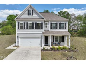 Charming two-story home featuring gray siding, black shutters, a well-manicured lawn, and an attached two-car garage at 3901 Bluffwind Dr, Raleigh, NC 27603