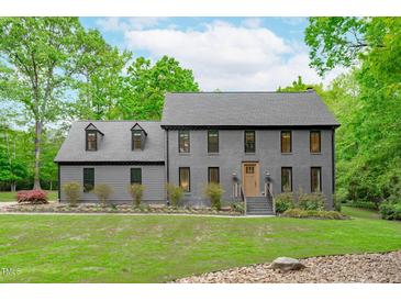 Charming gray two-story home with a lush green lawn and beautiful landscaping at 401 Brinkman Ct, Raleigh, NC 27614
