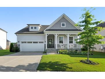 Charming home with a covered front porch, two-car garage, manicured lawn, and beautiful landscaping at 4333 Benton Mill Dr, Fuquay Varina, NC 27526