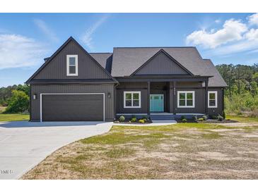 Charming exterior of home featuring a gray facade, well-manicured lawn, and a bright blue front door at 8629 Dukes Lake Rd, Zebulon, NC 27597