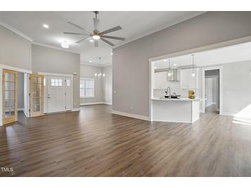 Bright living room with wood floors, ceiling fan, and open to the modern kitchen with a breakfast bar at 8629 Dukes Lake Rd, Zebulon, NC 27597