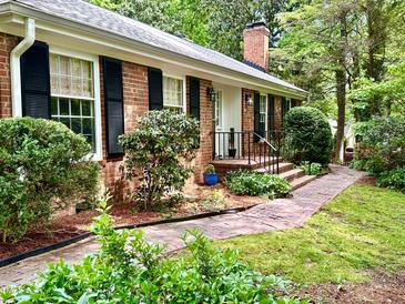 Charming brick home featuring black shutters, brick walkway, and professionally landscaped yard at 204 N Elliott Rd, Chapel Hill, NC 27514