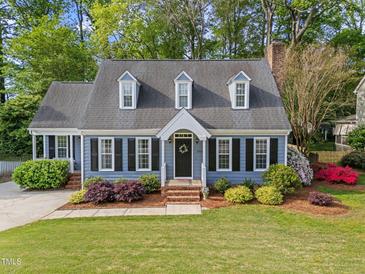 Charming blue two-story home with well-manicured lawn, lush landscaping, and black shutters at 2908 Bolo Trl, Raleigh, NC 27615
