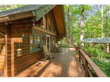 Expansive wooden deck features rocking chairs and overlooks lush greenery at 300 Rabbit Run, Pittsboro, NC 27312