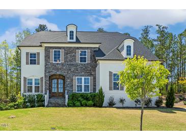 Charming two-story home featuring a mix of stone and painted brick and a well-manicured lawn at 304 Channel Cove Dr, Holly Springs, NC 27540