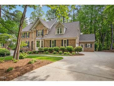Beautiful brick two-story home featuring manicured landscaping, dormers, and attached garage at 308 Hassellwood Dr, Cary, NC 27518