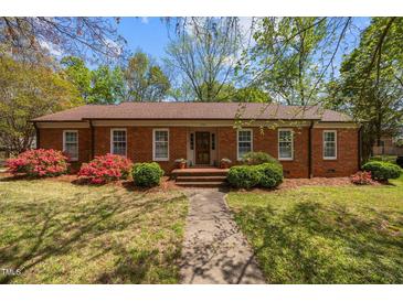 Charming brick home featuring a well-manicured lawn, mature trees, and beautiful flowering bushes at 3126 Truitt Dr, Burlington, NC 27215