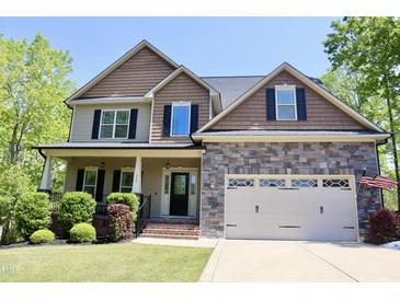 Charming two-story home featuring stone accents, a covered porch, and an attached two-car garage at 335 Gwendolyn Way, Fuquay Varina, NC 27526