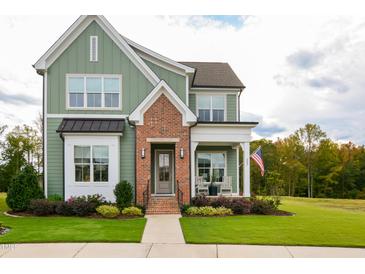 Charming two-story home boasts a brick-accented entrance, inviting porch, and manicured lawn, complete with vibrant landscaping at 337 Sunset Hill Ln, Wendell, NC 27591