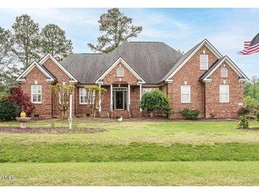 Charming brick home with a well-maintained lawn and mature landscaping under a partly cloudy sky at 4501 Forest Dr, Holly Springs, NC 27540