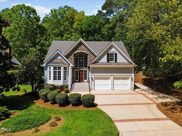 Charming two-story home featuring a stone facade, two-car garage, manicured lawn, and mature trees at 6819 Rainwater Rd, Raleigh, NC 27615