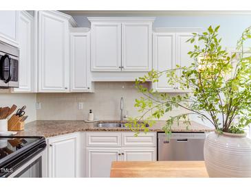 Bright kitchen features white cabinets, granite countertops, stainless steel appliances, and tile backsplash at 715 Barlang Cir, Fuquay Varina, NC 27526