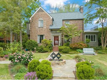 Charming brick home featuring professional landscaping, stone walkway, and a decorative water feature in the front yard at 1024 W Markham Ave, Durham, NC 27701