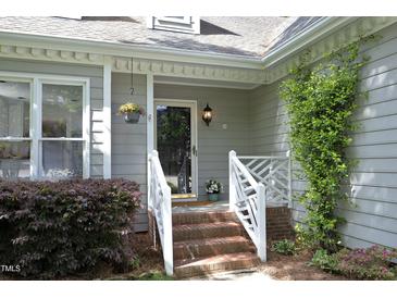 Charming home featuring a brick staircase leading to the front door, complemented by lush landscaping and a hanging flower basket at 104 Silver Fox Ct, Cary, NC 27511