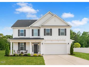 Charming two-story home with a welcoming front porch, attached garage, and professionally landscaped yard at 214 Thumper Way, Clayton, NC 27520